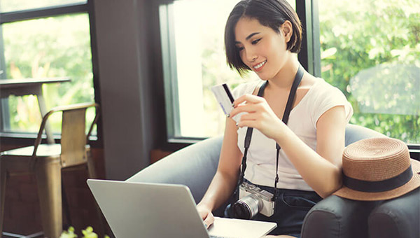 Woman holding a credit card shopping online at a coffee shop.