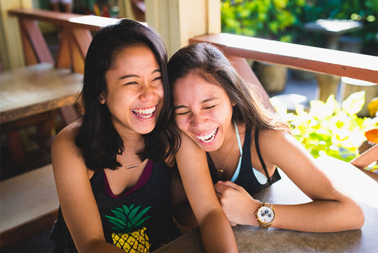 Girlfriends laughing on a restaurant veranda.