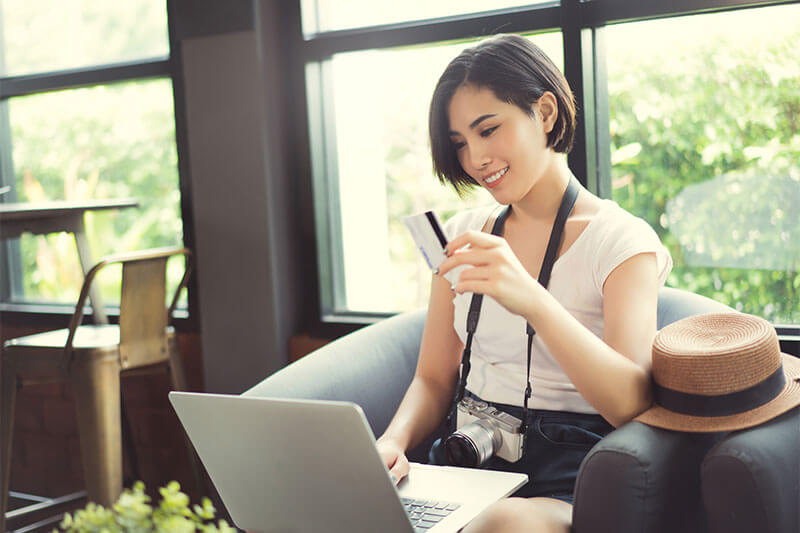 Woman holding a credit card shopping online at a coffee shop.