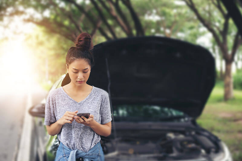 Woman using mobile phone to get help while looking stressed after her car has broken down.