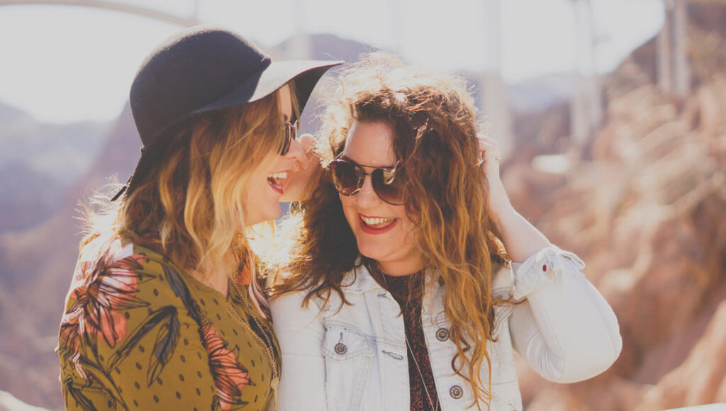 Two women laughing together outside on a sunny day