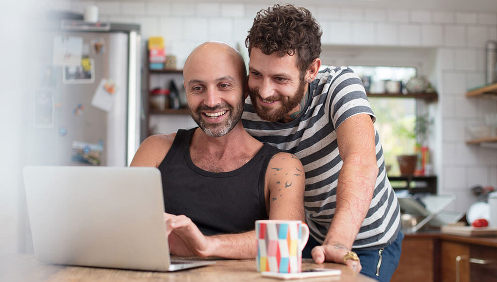 Couple using laptop for online banking in their kitchen