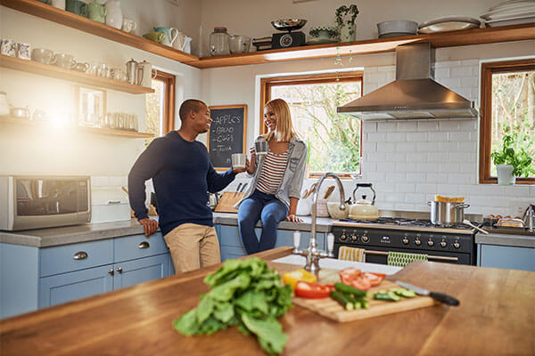 Young couple talking while having coffee in their newly-renovated kitchen.