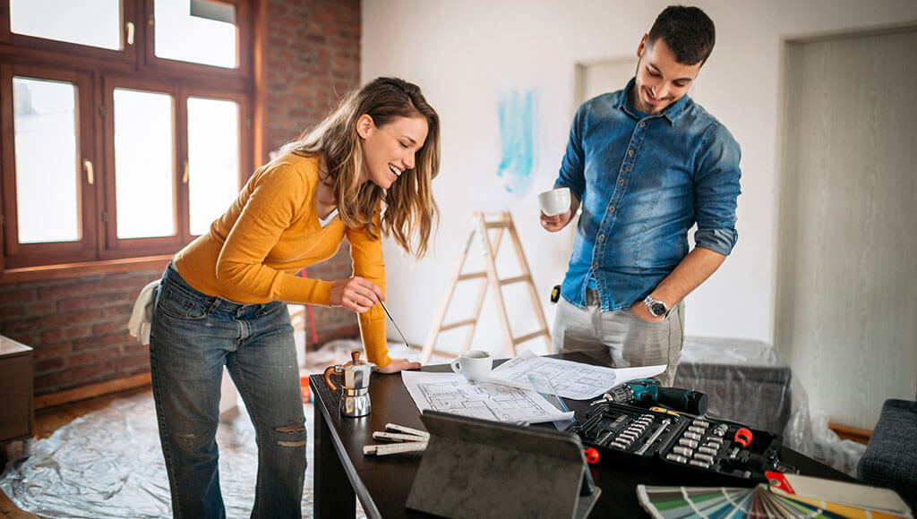 Young couple examining blueprints as they remodel their home.