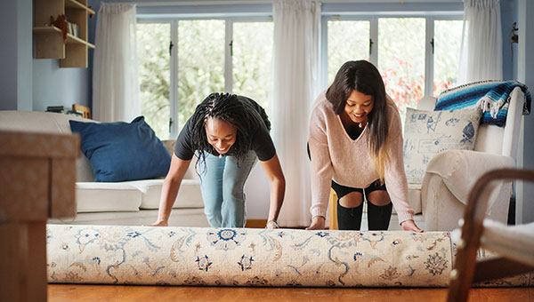 two women unrolling carpet in their new house