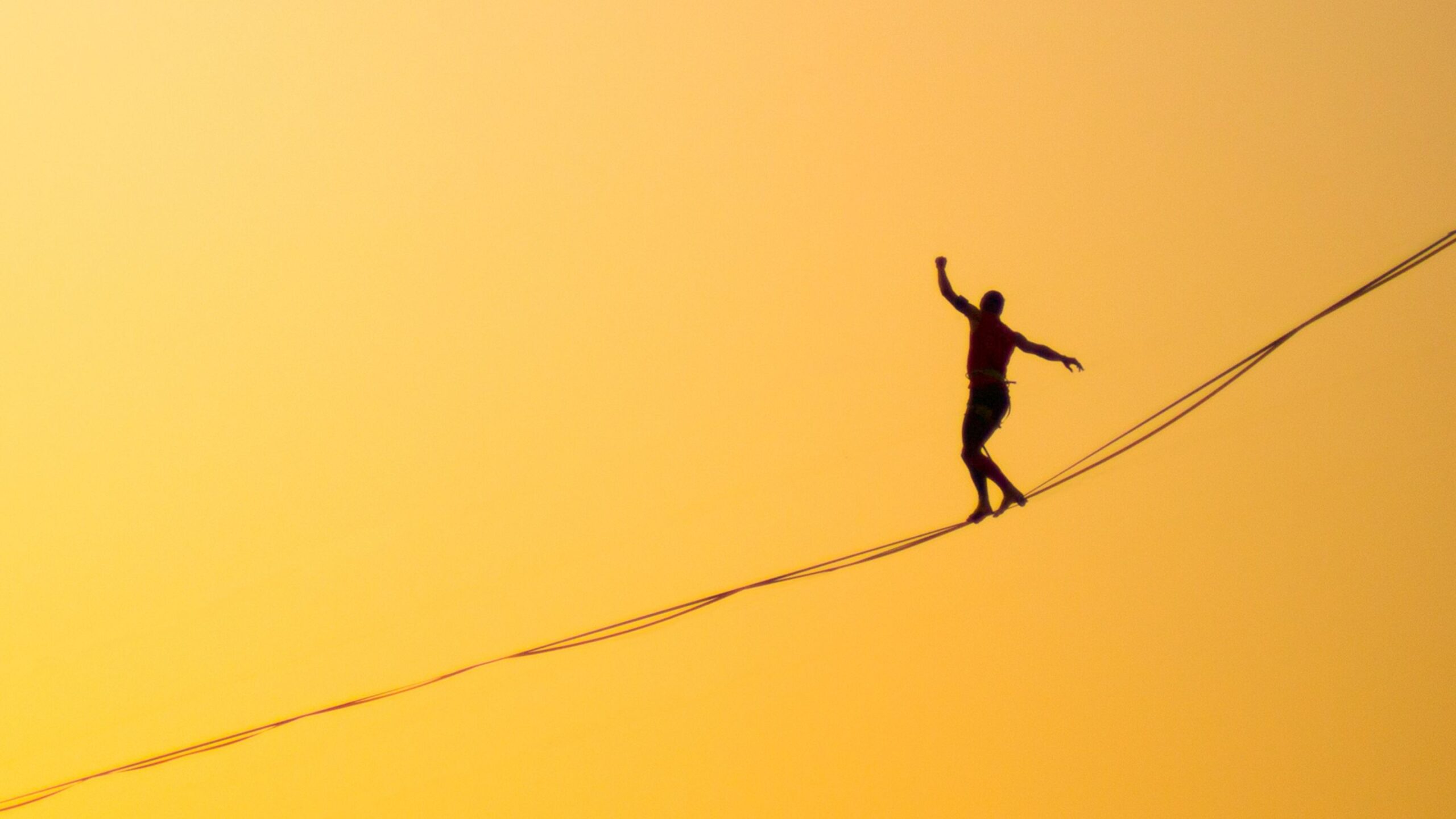 a silhouette of a man balancing on a wire