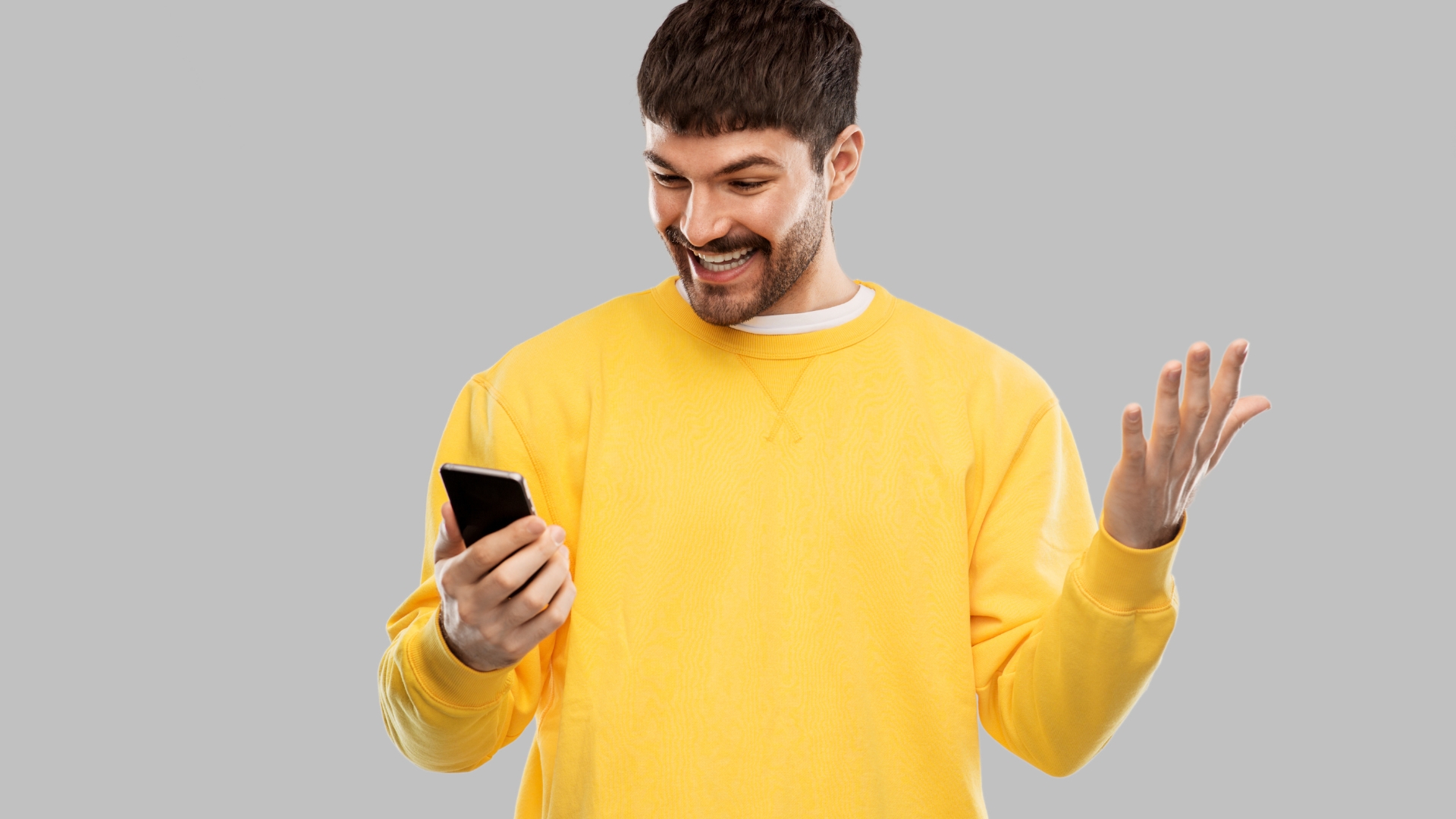 happy smiling young man with smartphone overgrey background.