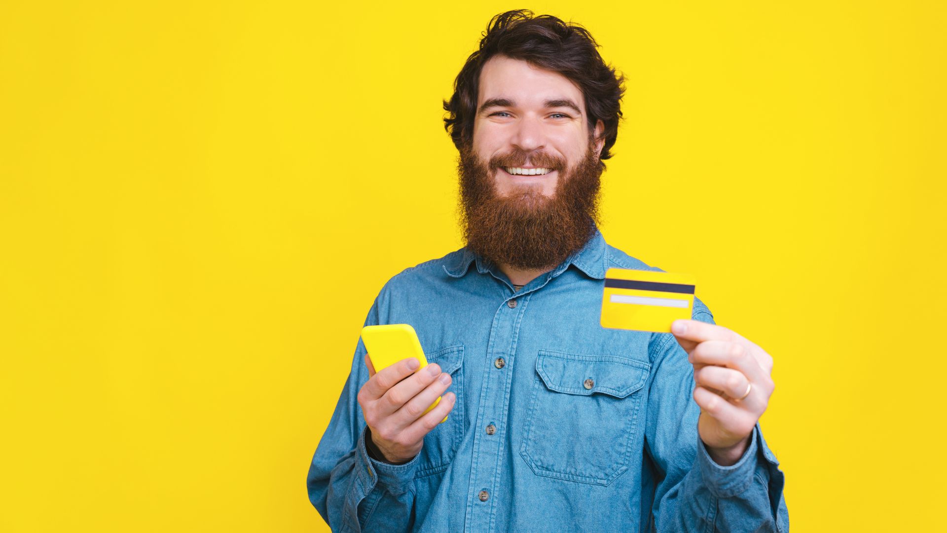 Happy young man showing his new yellow credit card