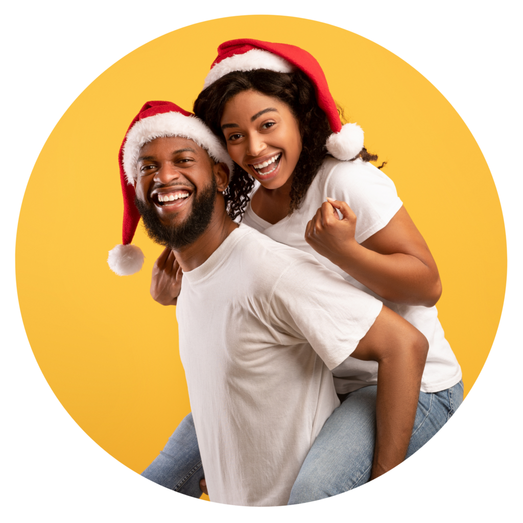 Guy Giving His Wife Piggyback Ride, Wearing Together Santa Hats, Yellow Background