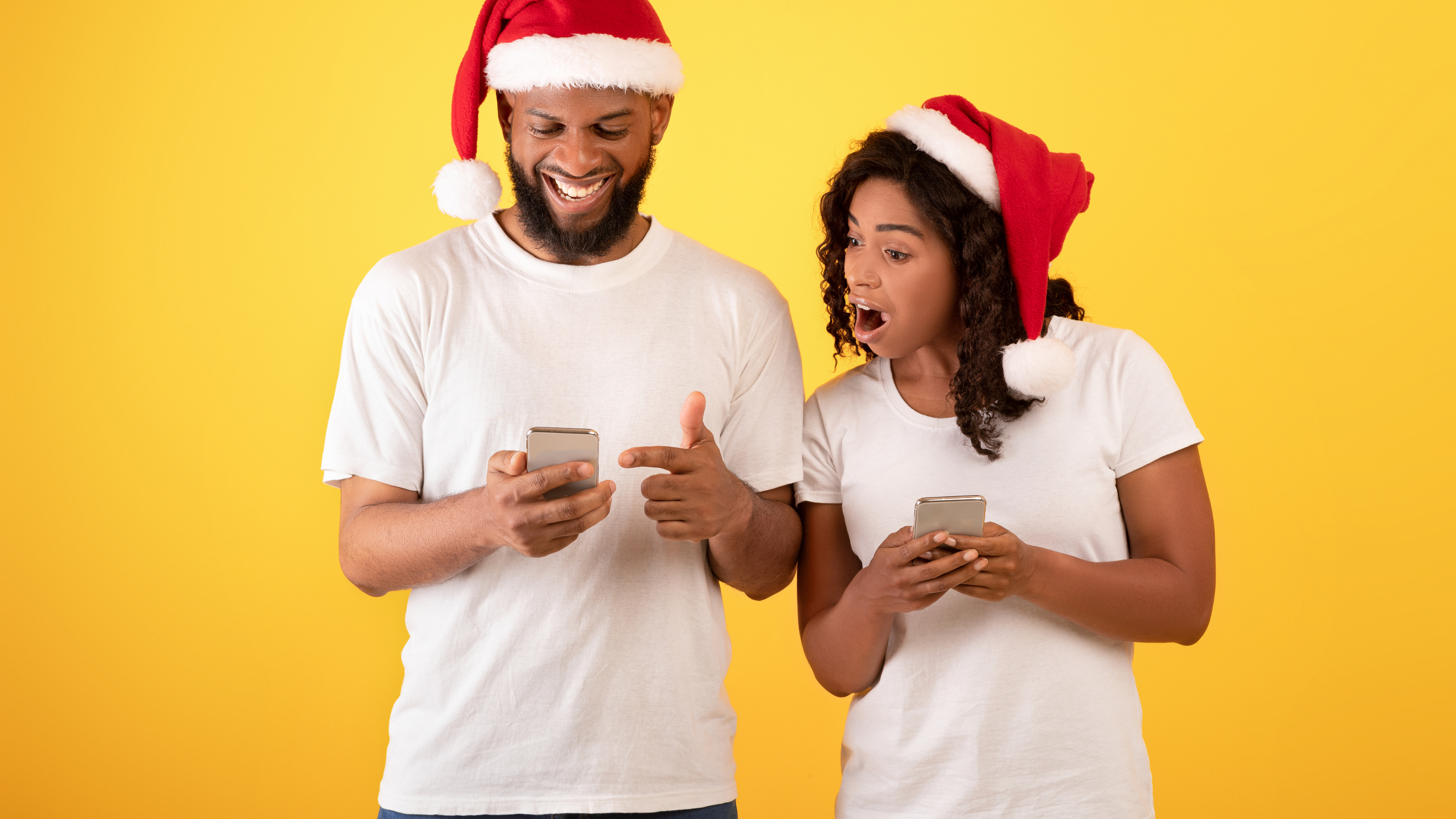 Wow Christmas mobile app. Surprised adults looking at smartphones, posing and wearing Santa hats