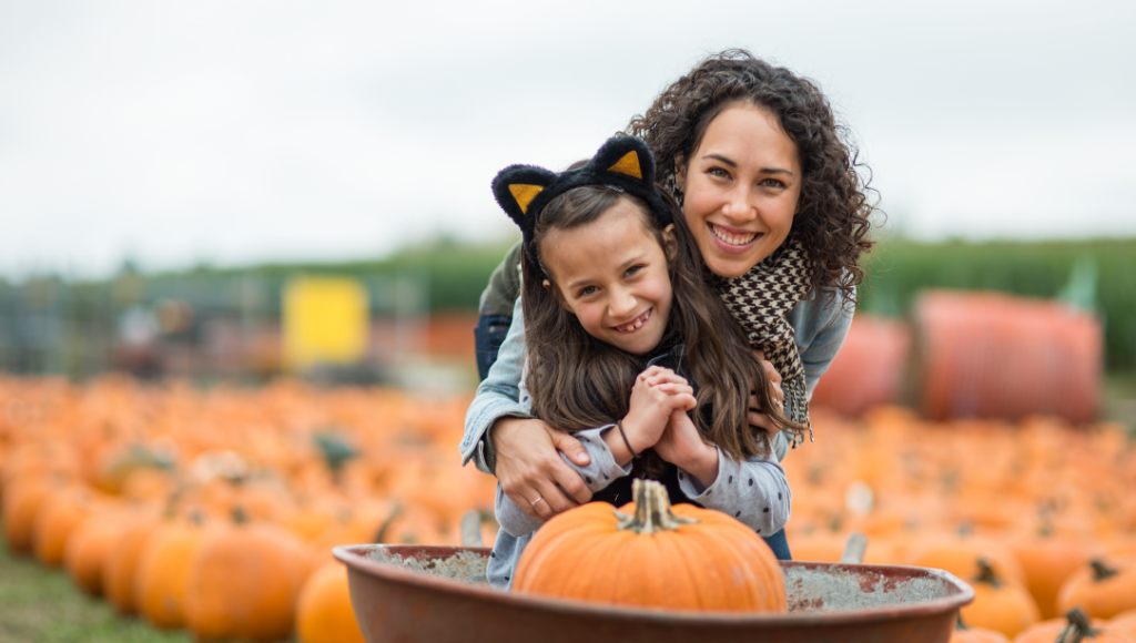 mother and daughter smiling in a pumpkin patch