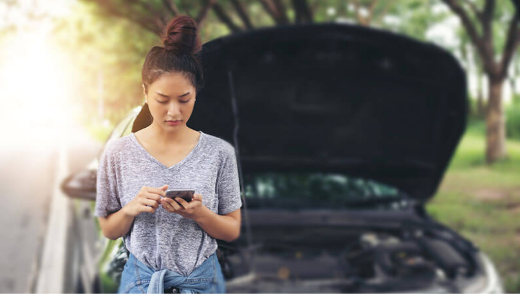 Woman using mobile phone to get help while looking stressed after her car has broken down.