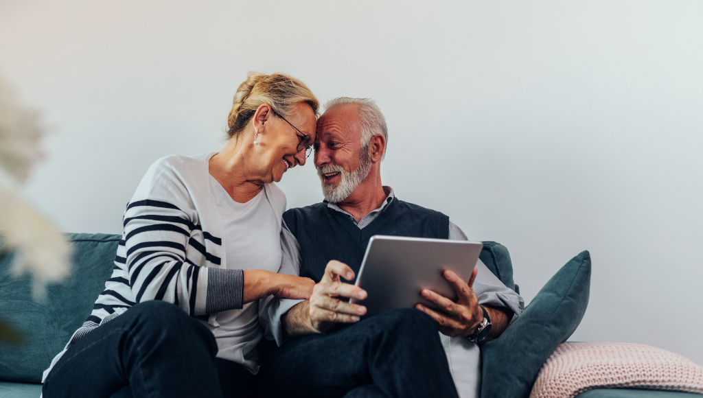 happy couple on couch holding tablet